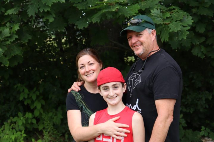 A man, his wife and young child smile at a camera