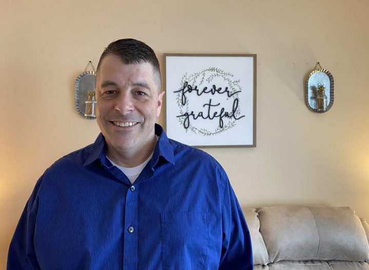 A man in a blue shirt smiles at the camera