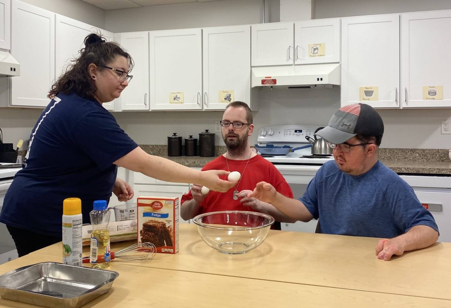 Two adults with disabilities practice cooking with help from Goodwill staff in Lifeworks program