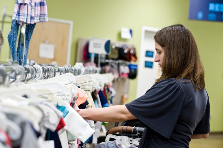 Young mom shopping in the children's clothing aisle at Goodwill store