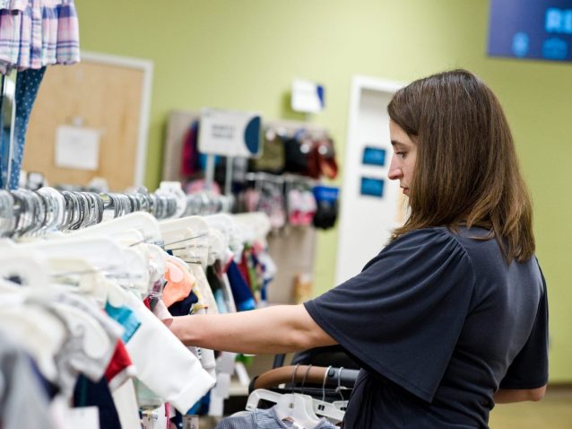 Young mom shopping in the children's clothing aisle at Goodwill store