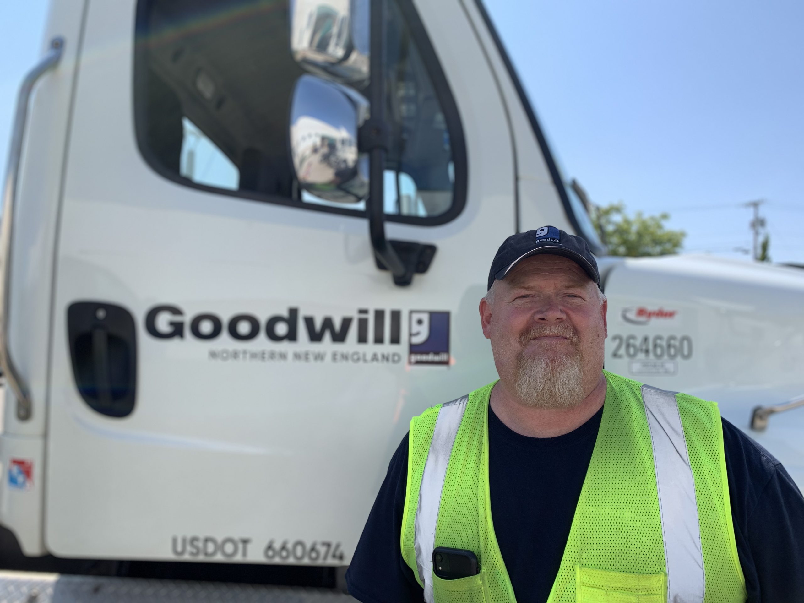 Man wearing yellow safety vest in front of a tractor trailer rig