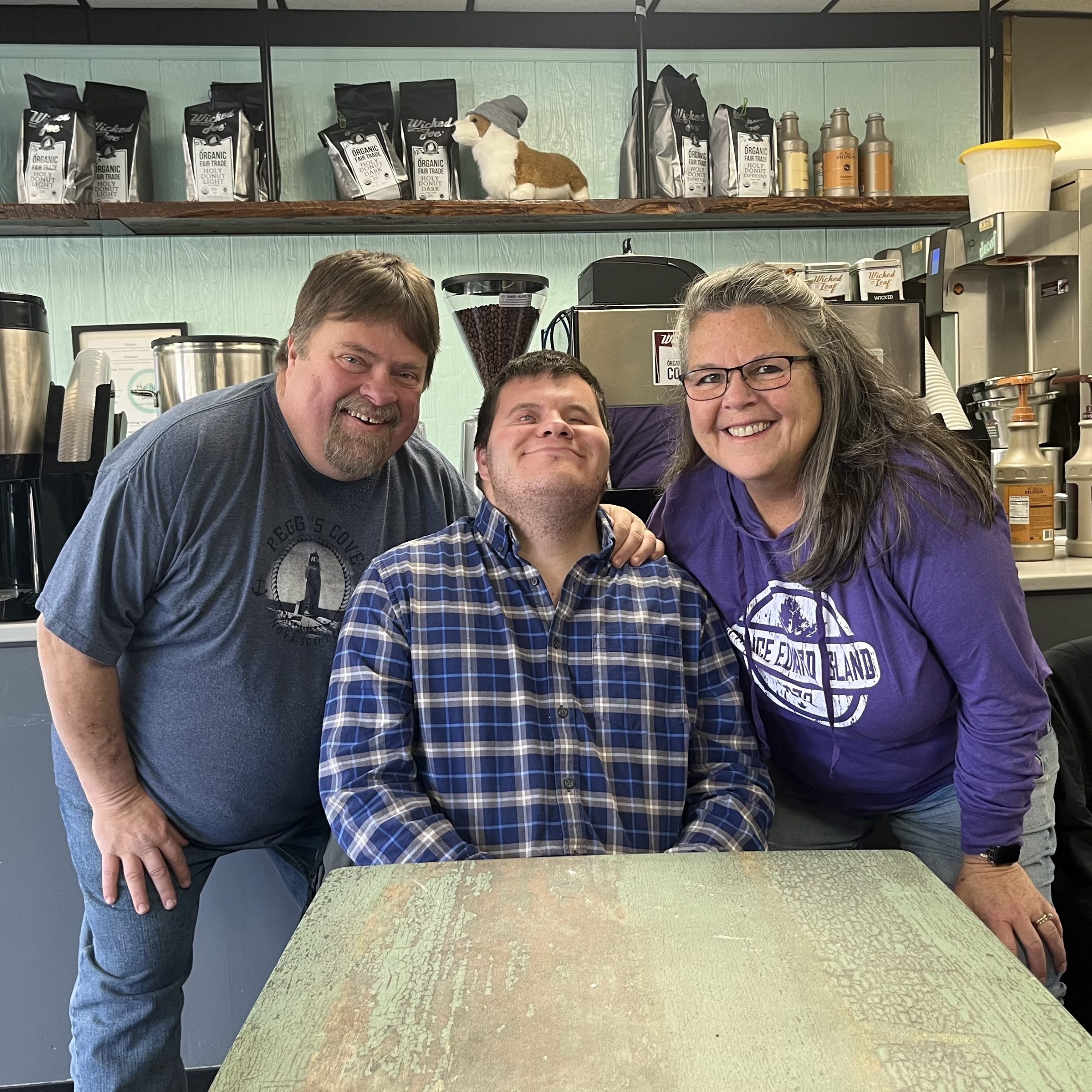 Jacob Allen (middle) sits smiling at The Holy Donut in Portland, with his parents on either side of him.