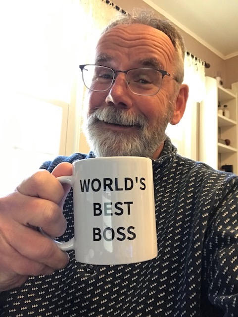 Man smiling and holding a mug that says "World's Best Boss"