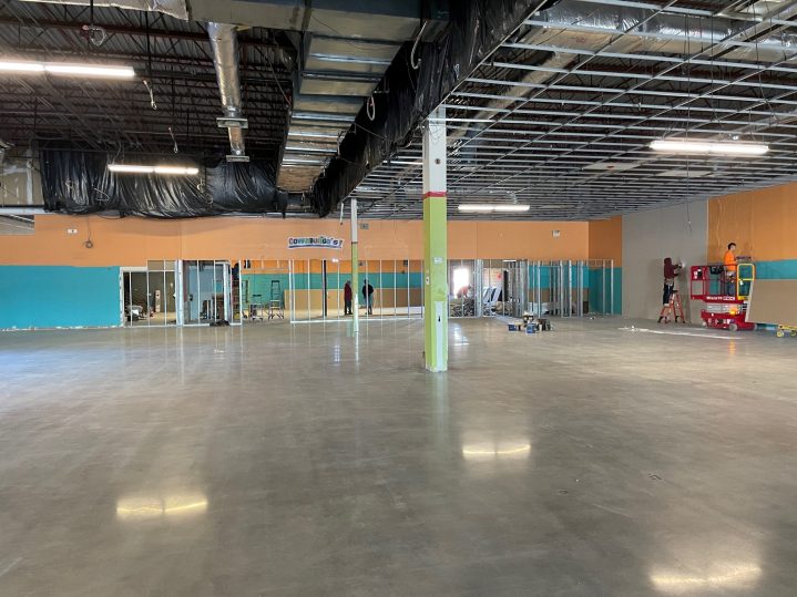 A large, empty room with no ceiling, very shiny waxed floors and a green painted beam in the middle.