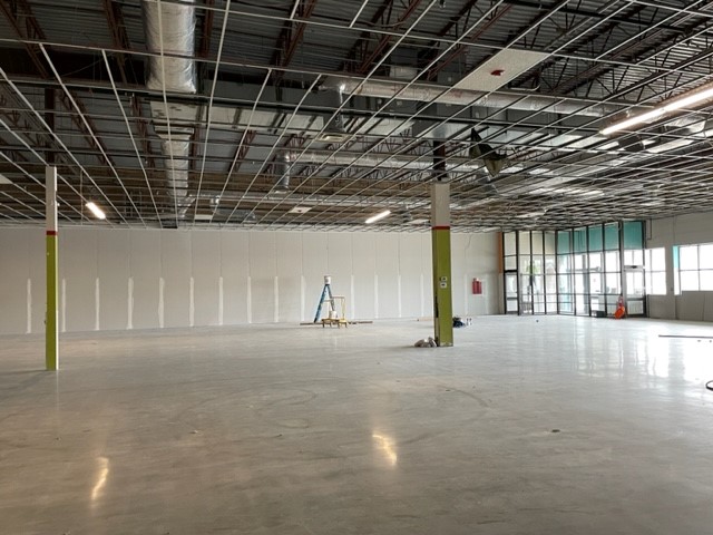 The side angle of a large, empty room with no ceiling, and very shiny waxed floors.