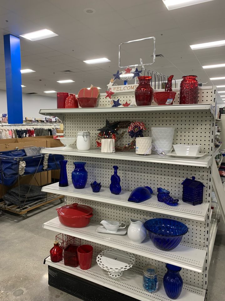 A Hardgoods shelf filled with breakable items like kitchenware, decor, and vases all organized by red white and blue. These can all be found at the new Goodwill NNE store opening in Hooksett, NH.