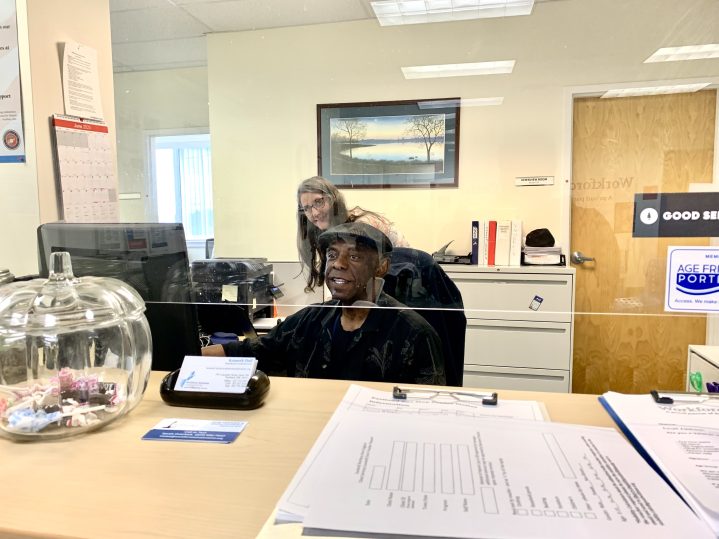 Ken Hull, with Workforce Solutions, greets people as they enter the office. His colleague, Rachel, stands behind him.