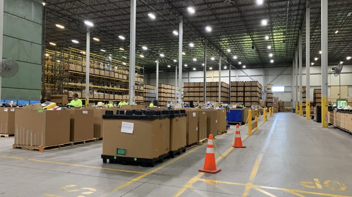 View of the warehouse at Goodwill NNE on the floor level. You can see lots of large boxes and people working.