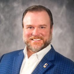 A man smiles in a blue suit