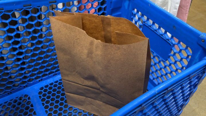 An empty paper bag in a blue shopping cart.