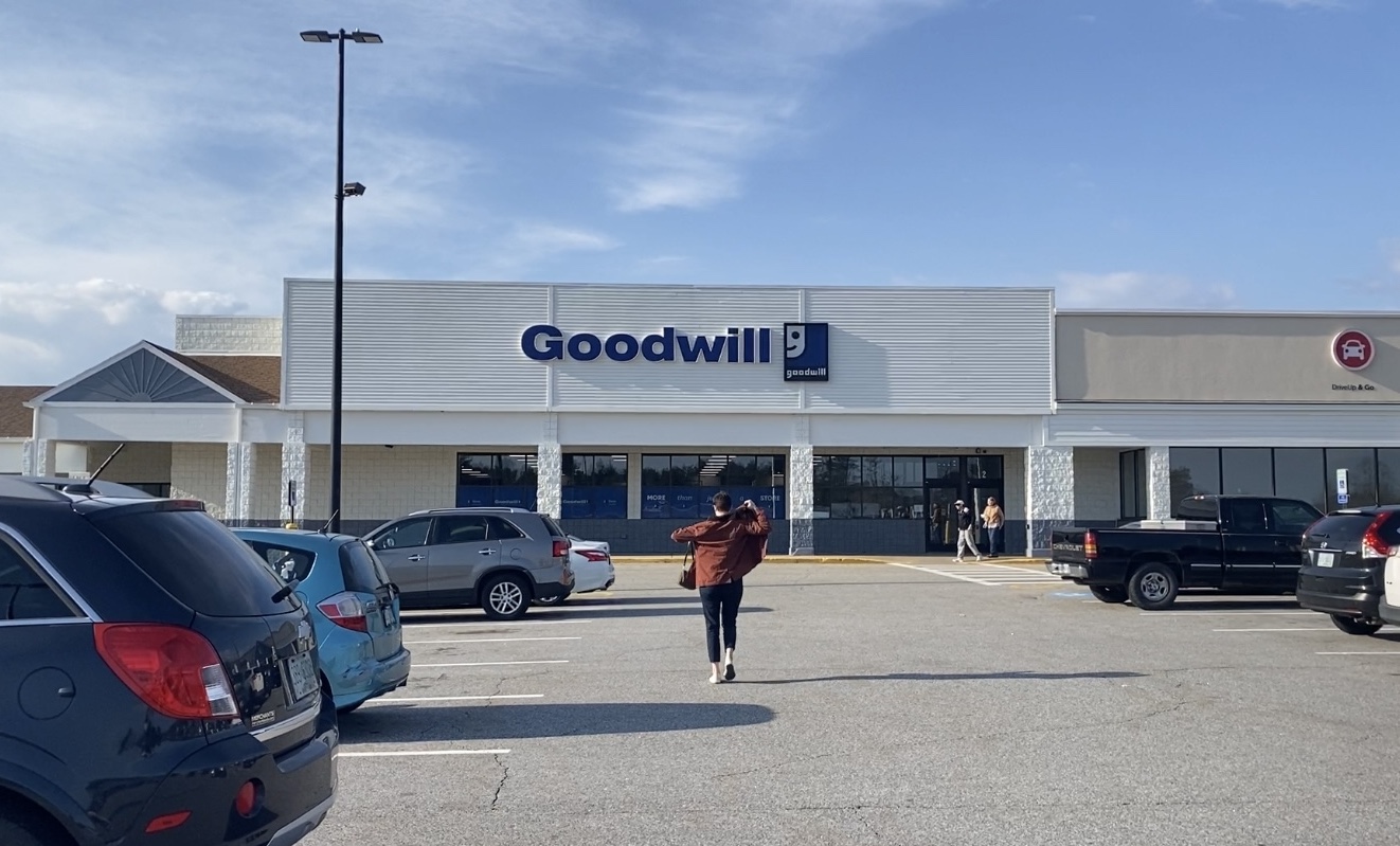 A person puts on a coat while walking toward a Goodwill store in Hooksett, NH