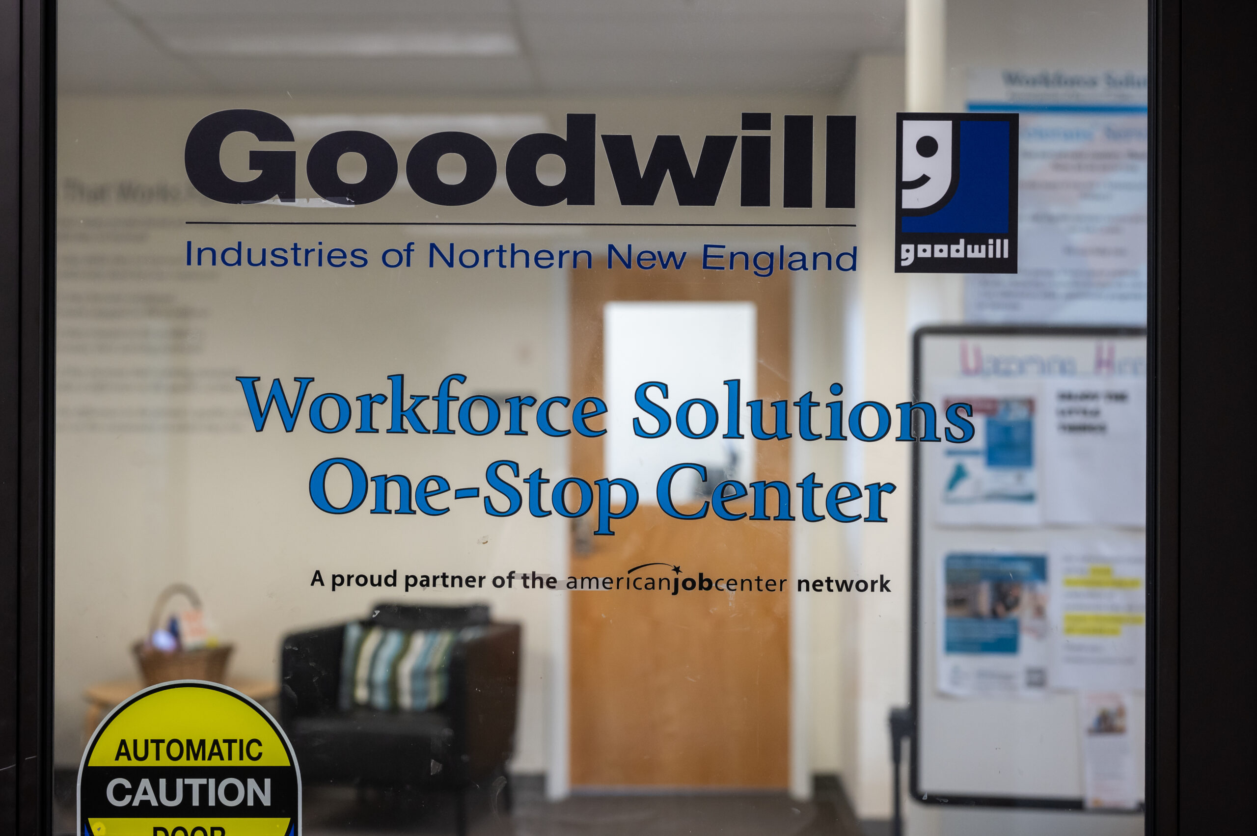 A glass door with decals that say, "Goodwill Northern New England Workforce Solutions One-Stop Center." The office provides upskilling services and career training to jobseekers.