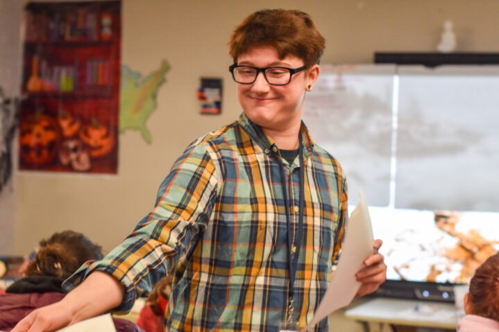 A Bootcamp career advisor handing out paper to a classroom of students.