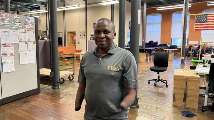 A man with no hands standing in a big workspace.