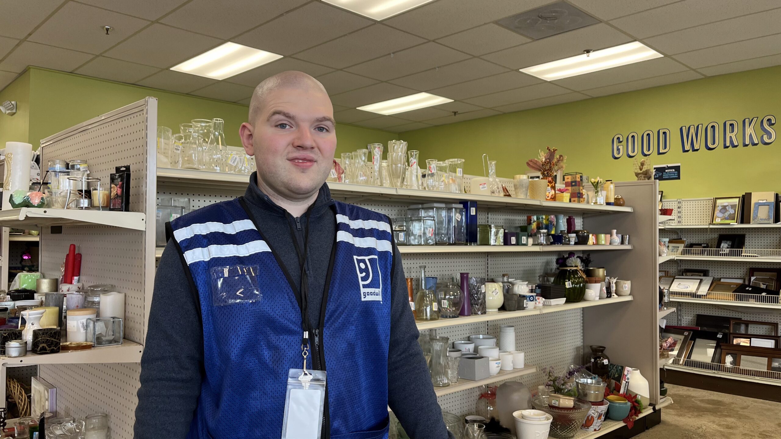A man standing in a Goodwill store with a blue vest
