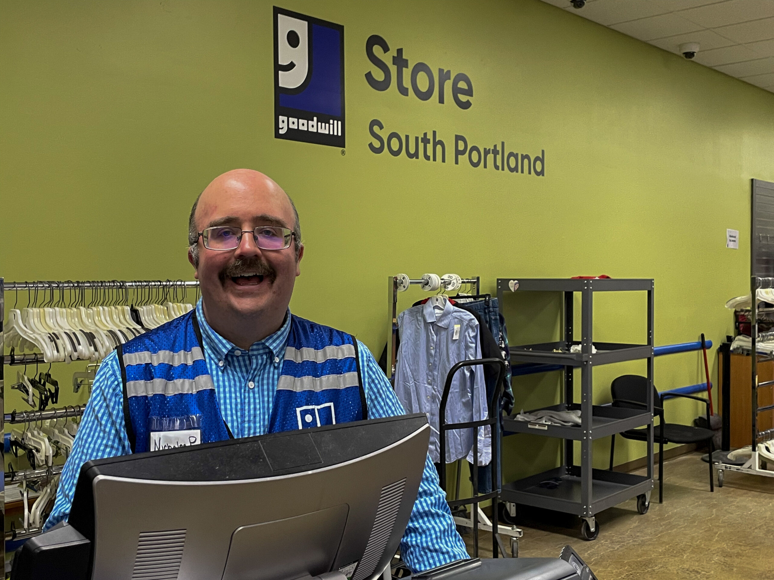 Man smiling at a cash register in a Goodwill store